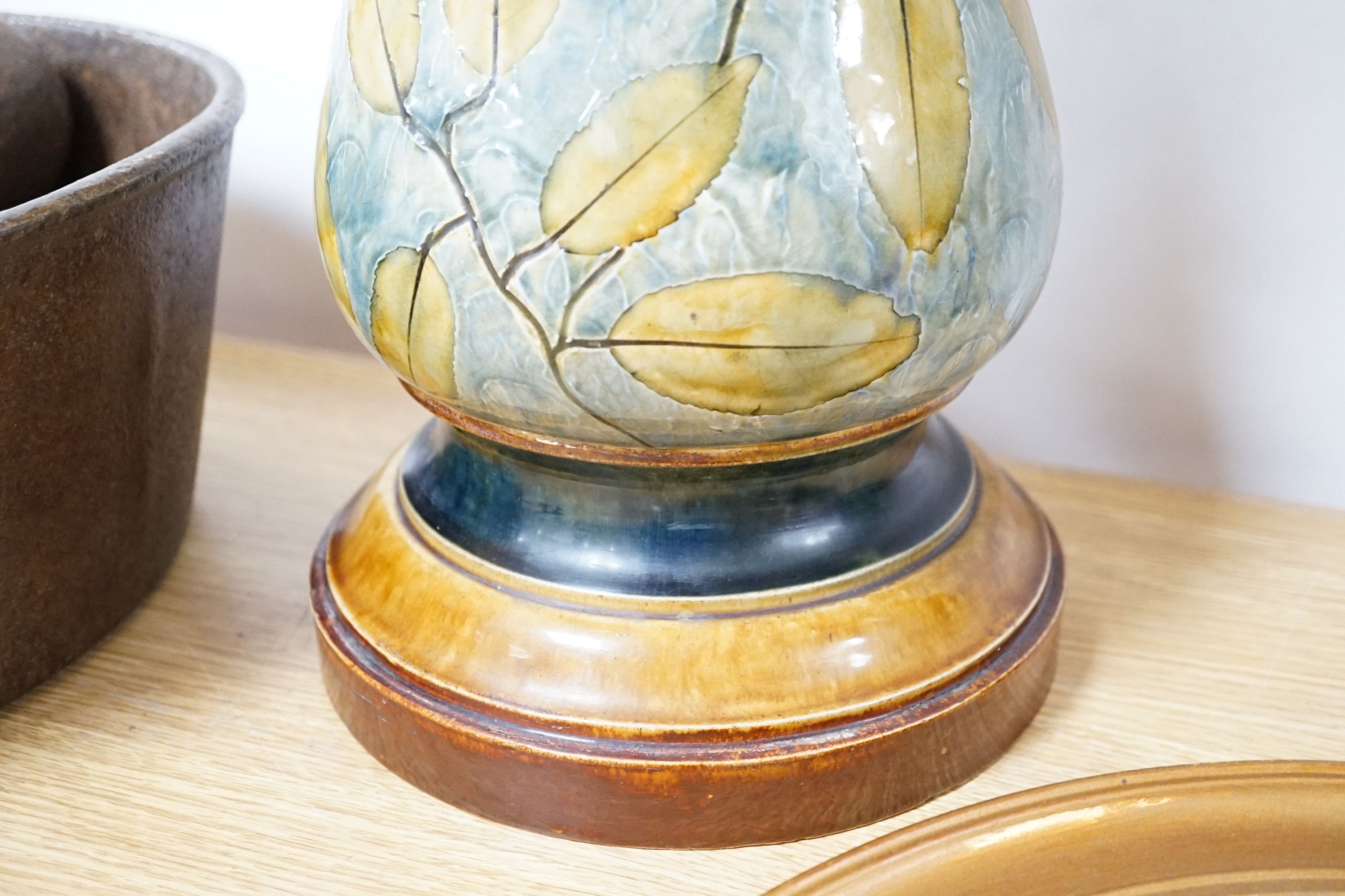 A Doulton, Lambeth Autumnal leaves jardinière on stand, 73cm high and a Burmantofts green glazed stoneware jardiniere stand, 62cm (3)